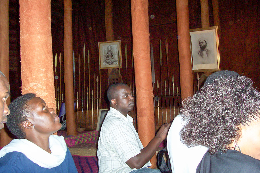 Listening to our guide in King Mwanga's Palace in Uganda